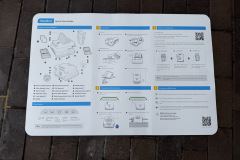 Ein großformatiges, bebildertes Poster zeigt die Schnellstartanleitung des Beatbot AquaSense 2 Ultra. Es ist auf einem Pflasterboden ausgebreitet. Zu sehen sind technische Zeichnungen des Roboters, eine nummerierte Schritt-für-Schritt-Erklärung zur Einrichtung, Hinweise zur App-Anbindung, zur Inbetriebnahme und zu Sicherheitshinweisen – alles ausschließlich in englischer Sprache.