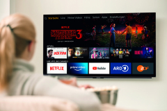 Big modern TV with 4k resolutions and young woman on foreground watching some video