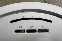 Nahaufnahme der Bedienelemente des Shark PowerDetect NeverTouch Pro. Drei Haupttasten zur Steuerung: Home, Start/Stopp und Wischen. Darüber eine Statusleiste mit Symbolen für WLAN, Akku und Warnhinweise.