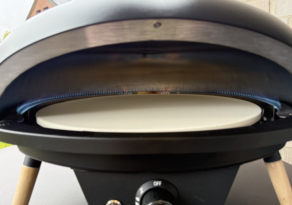 Blick in den aufgeheizten Le Feu Turtle Motion Pizzaofen mit sichtbarer Gasflamme und Pizzastein.