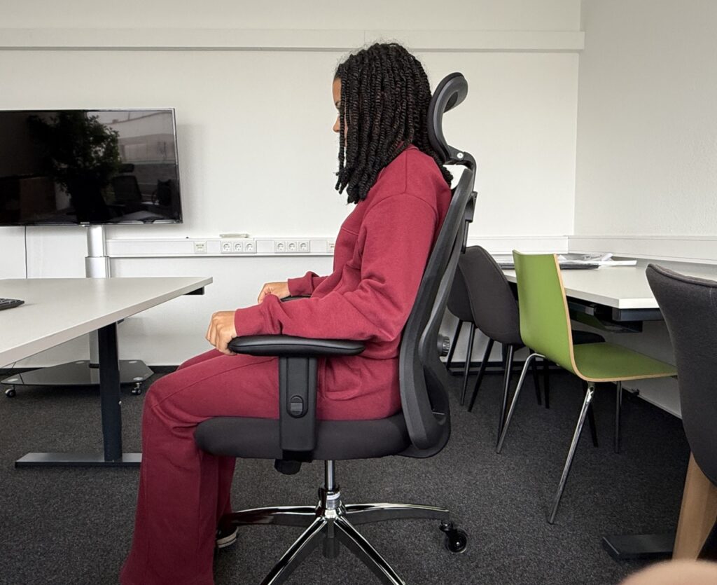 Person sitzt aufrecht auf dem Sihoo M18 an einem Schreibtisch.