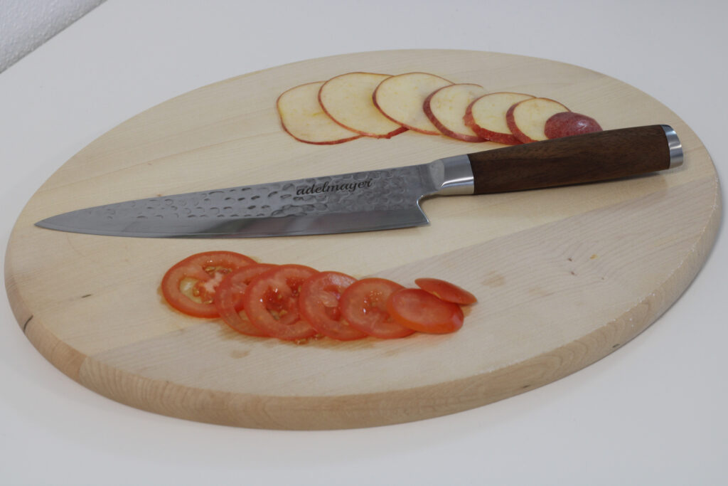 adelmayer Damastmesser Küchenmesser 20 cm 2077 Gesamtansicht mit geschnittenem Apfel und geschnittenen Tomaten auf Brett